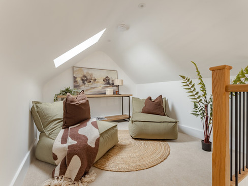 Cozy loft snug with skylight, beanbag seating, round jute rug and soft neutral décor beneath a sloped ceiling.