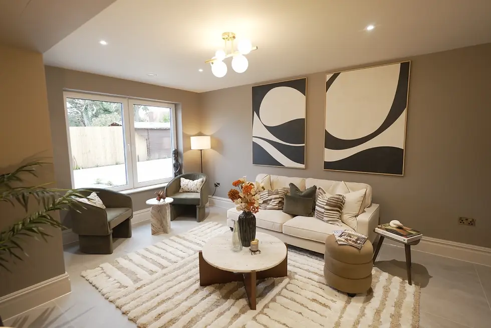Modern living room with beige sofa and striped pillows, round table with flowers, abstract art, and large window. Cozy and stylish ambiance.