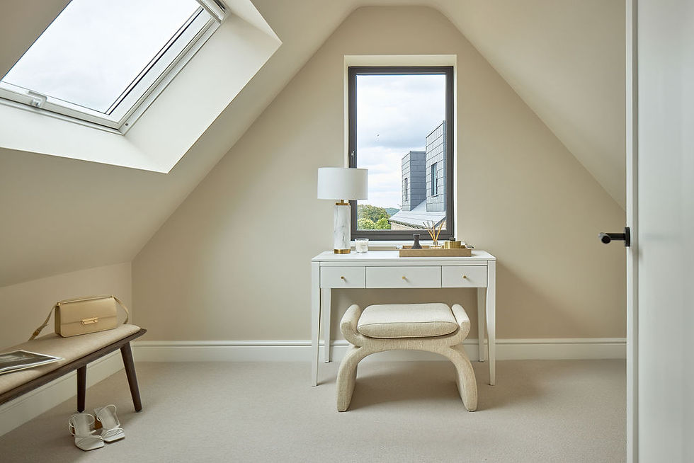 Modern attic room with cream walls, a skylight, and a window view. White desk with a lamp, bench with a purse and shoes beneath it.