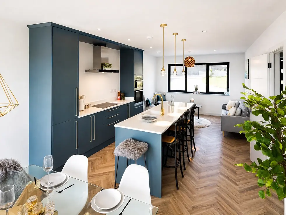 Modern kitchen with blue cabinets, white countertops, and a wooden herringbone floor. Dining area and plants create a cozy ambiance.