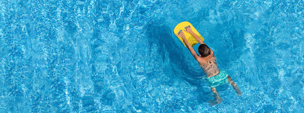 Boy child swim in swimming pool using board Active wellness summer vacation in resort hote