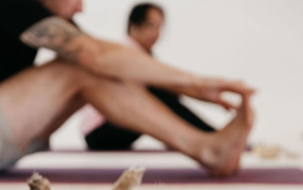 Stretching pose during Puppy Yoga with pup lying nearby