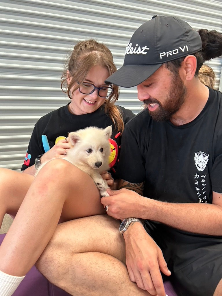 Photo of a couple holding a Spitzky puppy at a Puppy Yoga class