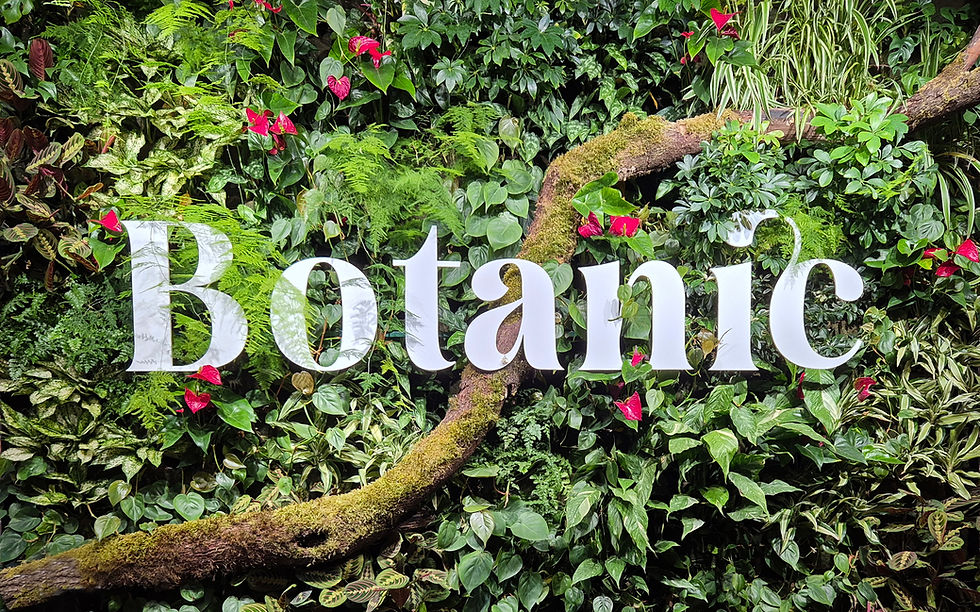 Botanic Bar & Events Logo vor grüner Pflanzenwand im Eingangsbereich