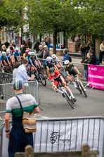 Ilkley town centre cycle race competitors turn right between the metal barriers.