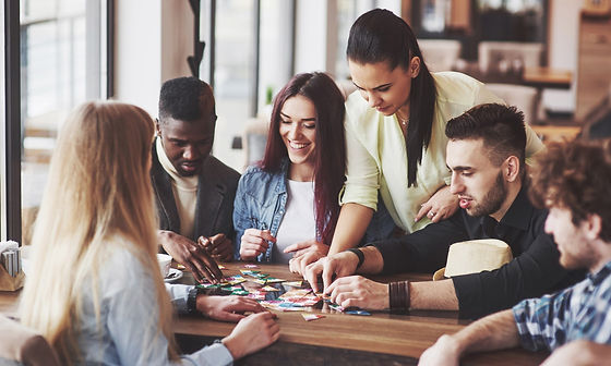 Group of friends enjoying a board game together at a wooden table, smiling and focused, creating a fun and social atmosphere