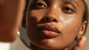 Eine Frau die in einen kleinen Handspiegel ihr inneres reflecktiert