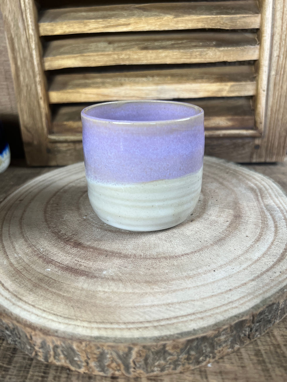 Miniature : Petite tasse artisanale en grès lilas et crème posée sur support en bois naturel