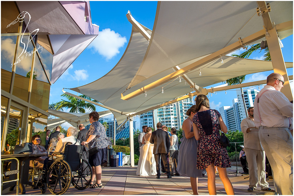 Van Wezel Wedding Photography, guests mingle on the terrace during the cocktail hour, downtown Sarasota in the background.