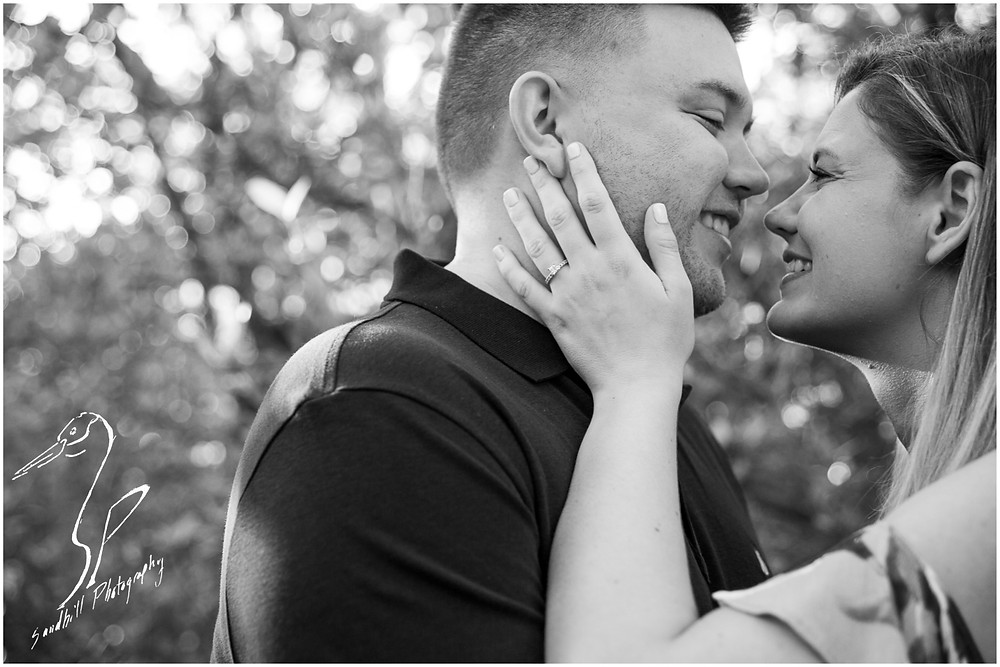 DeSoto National Memorial Photography, a woman places her hand on her fiance's on her fiance's face, displaying her engagement ring, and draws him close. Bradenton FL