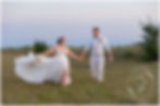 Sarasota Wedding Photographer Resort Wedding bride and groom walk through a field of sea grass as the wind blows the train of her wedding gown