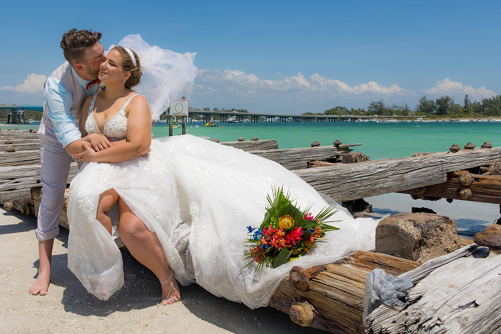 Sarasota Wedding Photographer the groom gives his bride a kiss infront of the turquoise waters of Sarasota Bay