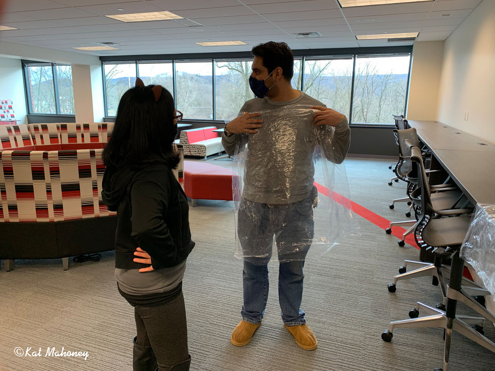 Two people in an office, one wearing plastic wrap.