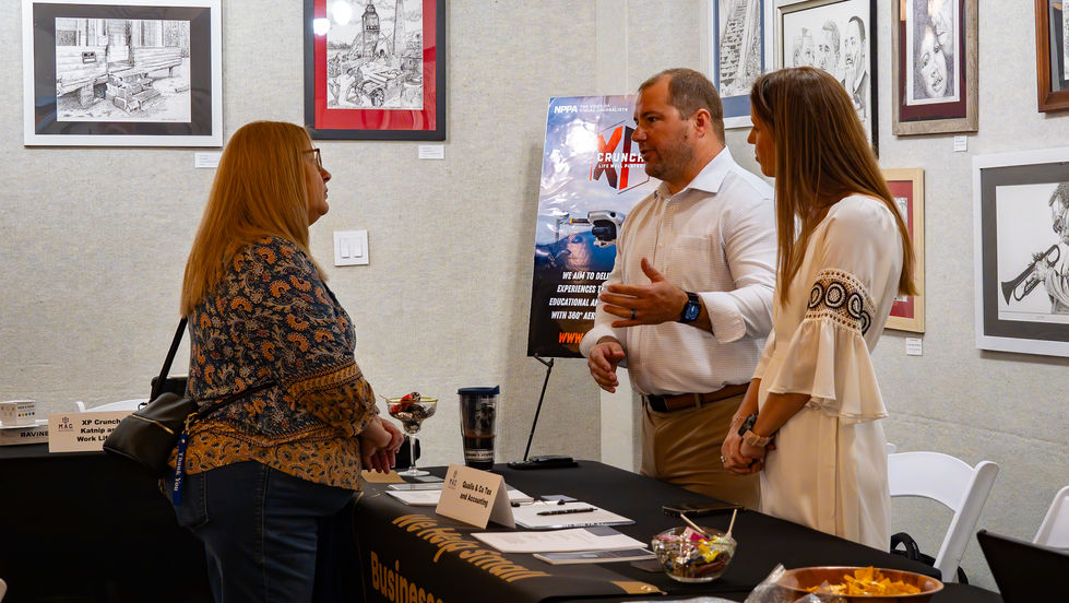 Three people discussing at an indoor event.
