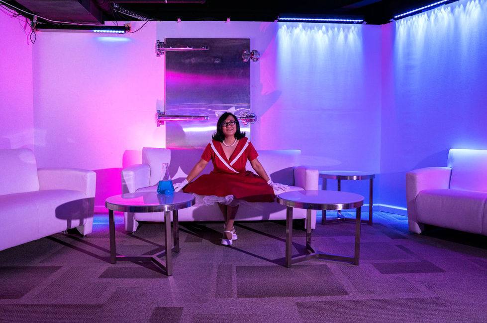 Woman in red dress sitting in colorful room.