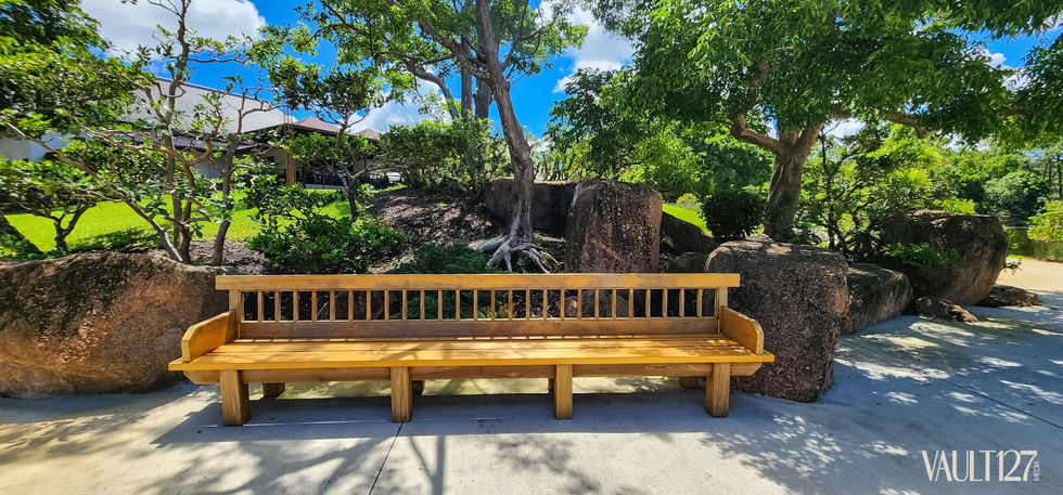 Wooden bench under trees in a sunny park.