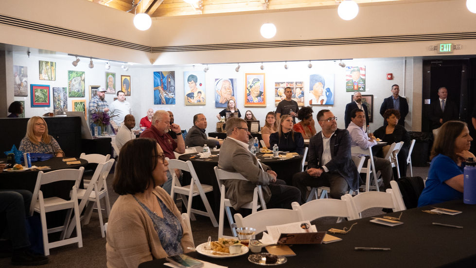 People seated at an event with artwork displayed.