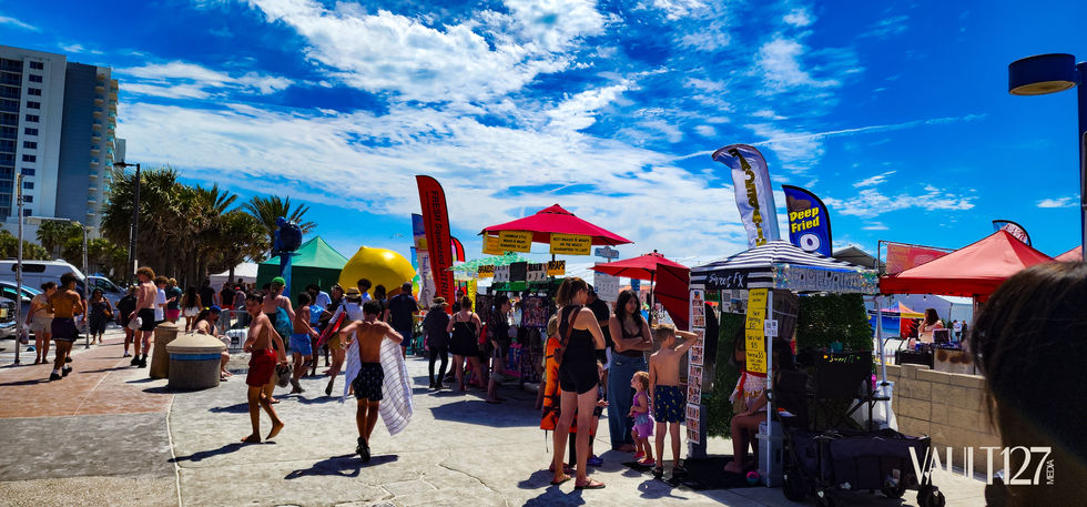 People at a vibrant outdoor market with umbrellas.