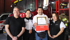 personas frente a una patrulla de bomberos sosteniendo un diploma
