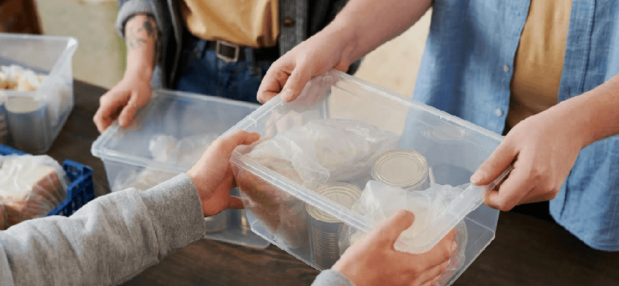 manos de personas con una caja plástica de alimentos