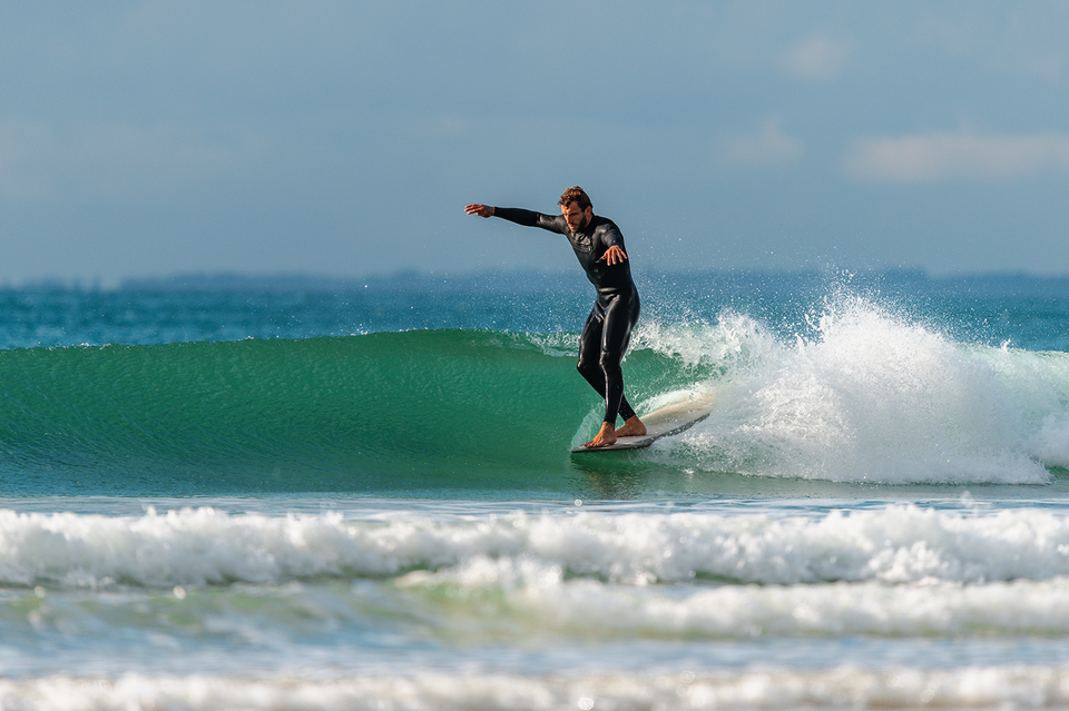 Skilled surfer hanging five in the pocket of a glassy knee-high wave.
