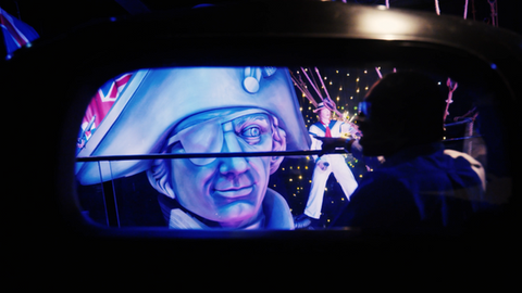 Over-the-shoulder view of actor on ride with Nelson wax figure in background.