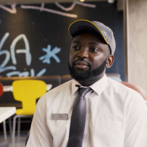 McDonald’s employee seated in a restaurant, speaking to camera during a filmed interview.