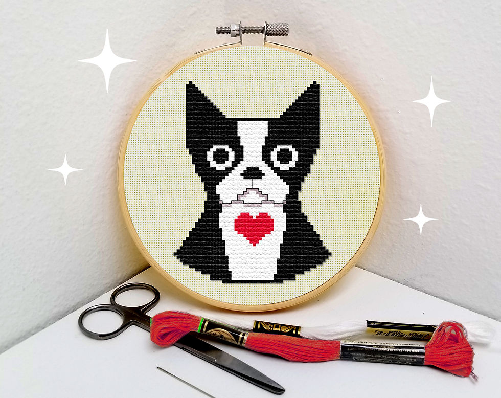 Thumbnail: A small cross stitch of a Boston Terrier dog with a cute heart detail is framed in an embroidery hoop next to red floss