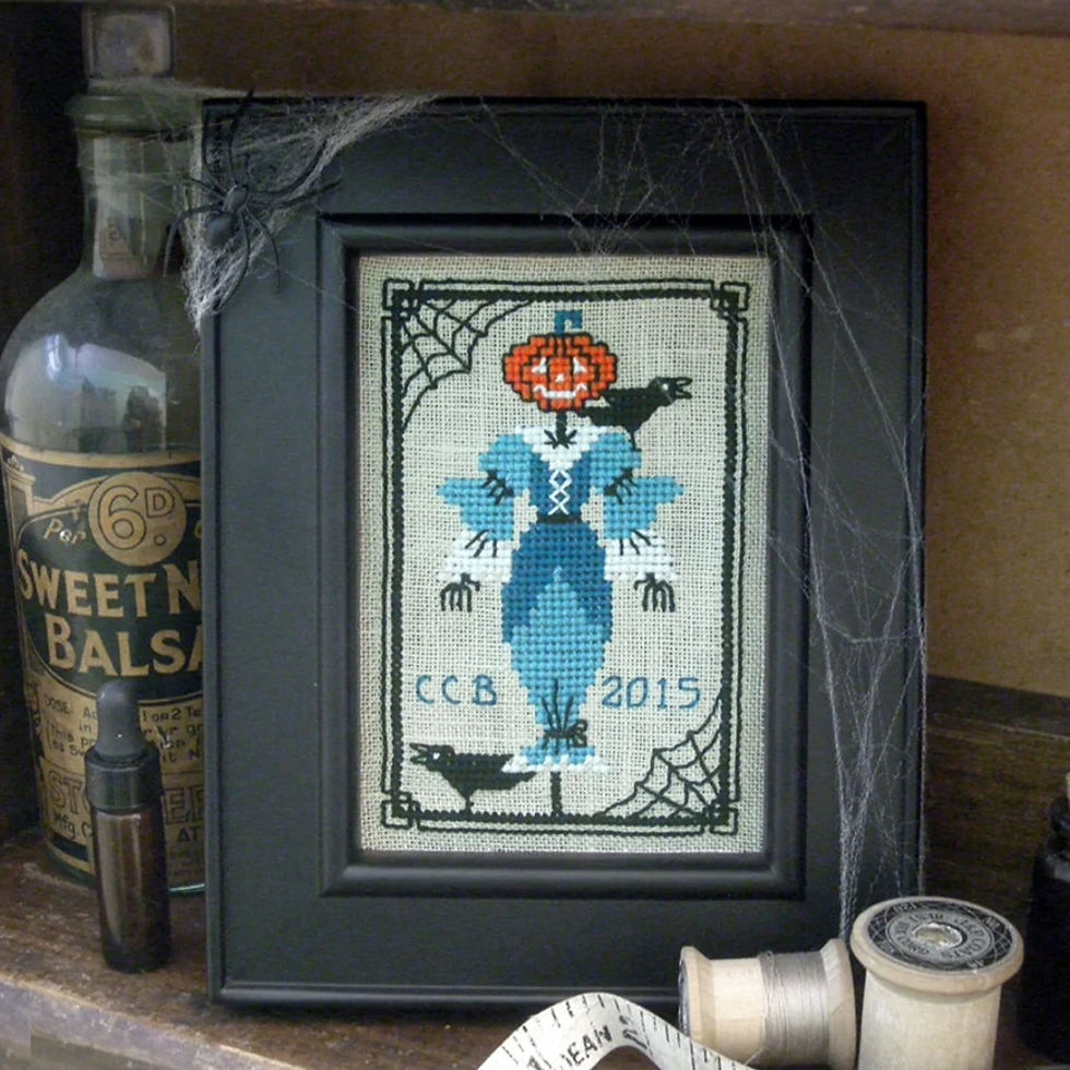 Thumbnail: A primitive style jack o lantern pumpkin head scarecrow and raven cross stitch pattern download.