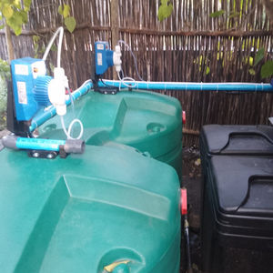 Two seko dosing pumps and green dosing tanks with chlorine and sodium hydroxide chemical drums.