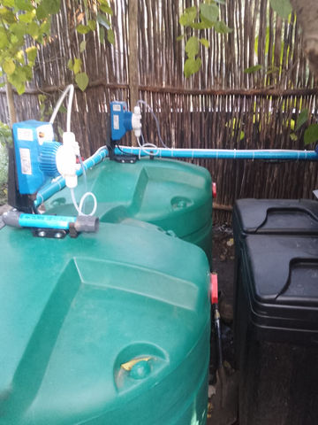 Two seko dosing pumps and green dosing tanks with chlorine and sodium hydroxide chemical drums.