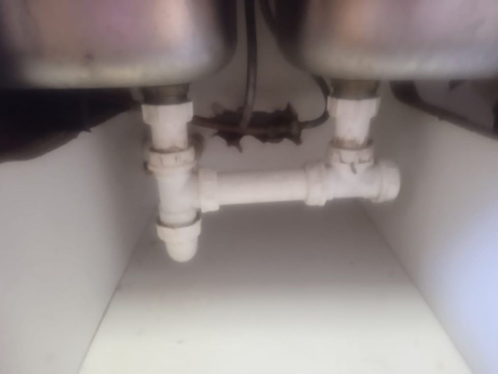 double sink underneath a white cabinet with white pipes