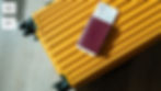 Yellow suitcase with a maroon passport and boarding pass on top, set against a light wood floor. Labels "A2" and "B1" appear on the left.