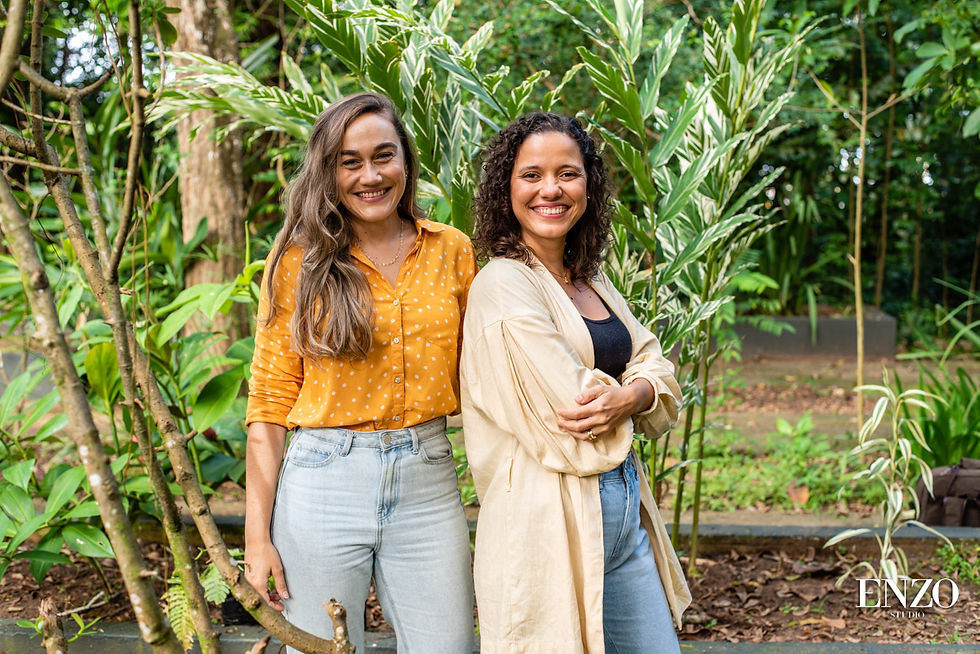 duas mulheres sorrindo em meio a muitas plantas e árvores