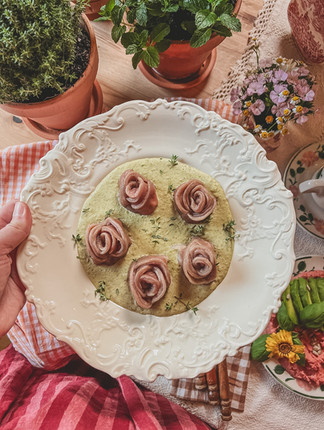 a plate of rose shaped pasta with herbs and spring like background