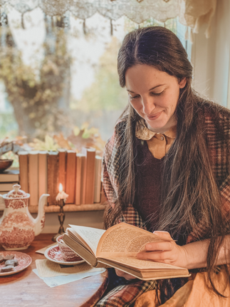 A woman reading a book in a candlelit cozy room.
