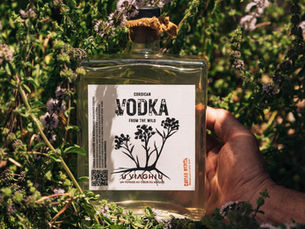 Corsican wild vodka bottle infused with citron and wild nepitella mint, surrounded by maquis herbs