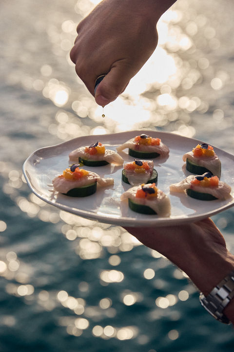 Kingfish crudo with cucumber and citrus being dressed with high quality olive oil