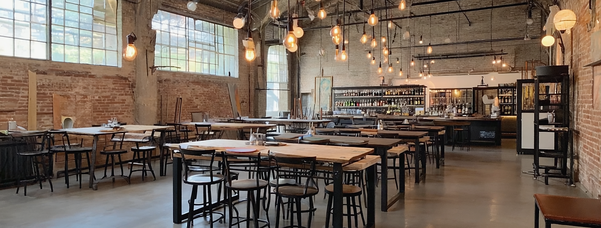 Karol's Collective art workshop venue in Scottsdale featuring exposed brick, high ceilings, communal tables, and pendant ligh
