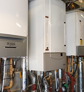 Commercial boiler units installed in a row with piping.