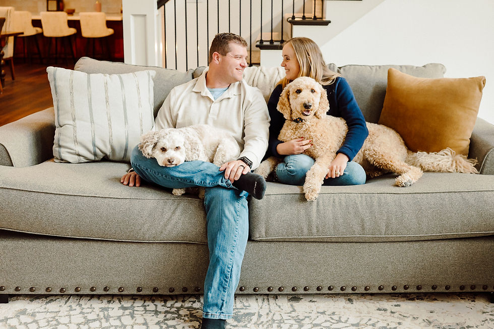 young man and woman sitting on couch in warm neutral tones looking lovingly at each other and cozy