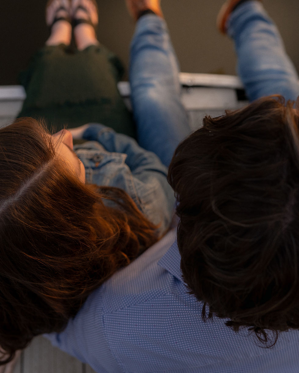 young couple sitting on dock feet dangling over water