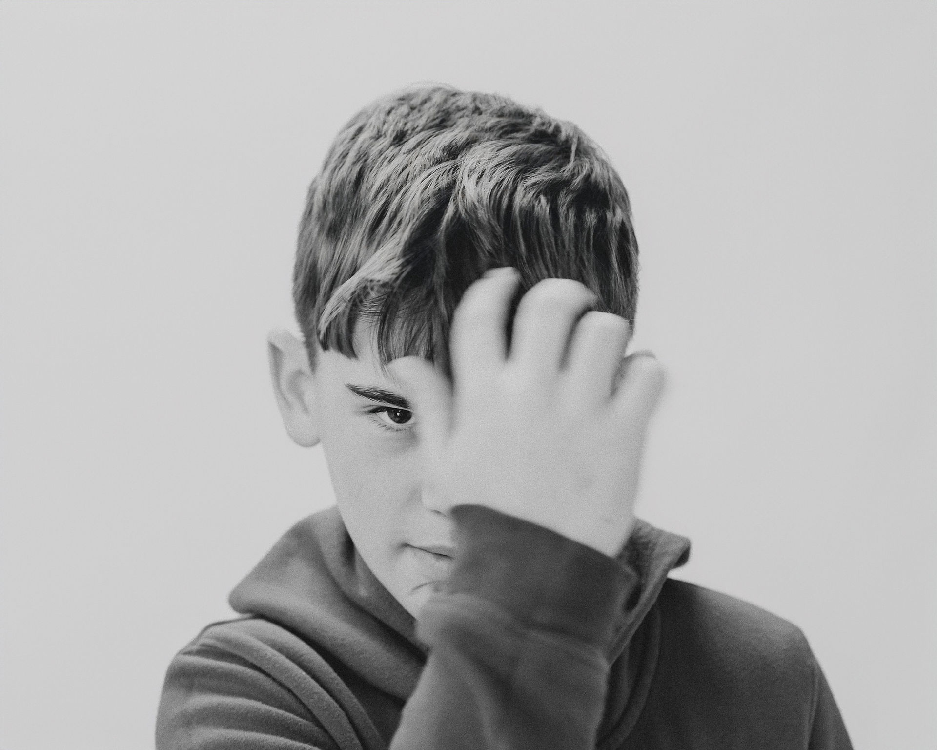 Boy looking at camera in solid background and black and white image adjusting his hair