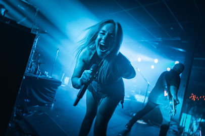 Devilskins lead singer, high energy, stage lights, blue tones.