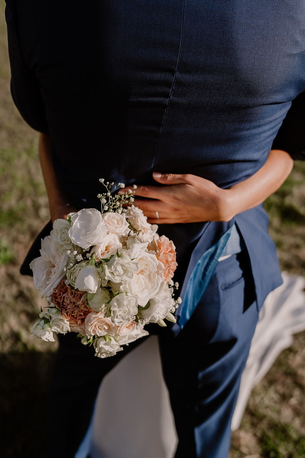Couple de jeunes mariés enlacés, détail du bouquet de fleurs