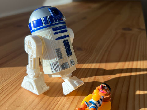 Ein Fauler Mann liegt rum und wird von einem Roboter gesteuert.