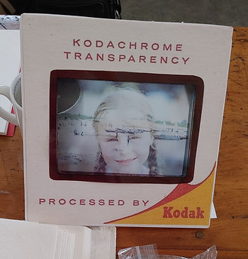 Close-up of a Kodachrome slide showing a smiling child at the beach. Text reads "KODACHROME TRANSPARENCY, PROCESSED BY Kodak."