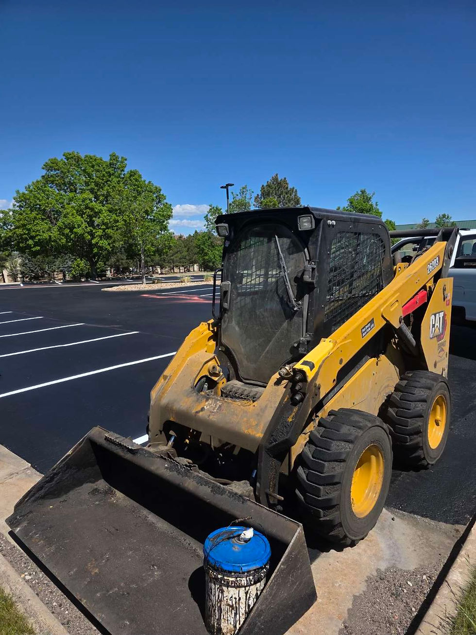 Yellow skid steer on new asphalt paving