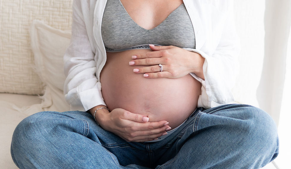 Pregnant woman seating leg crossed holding her bump