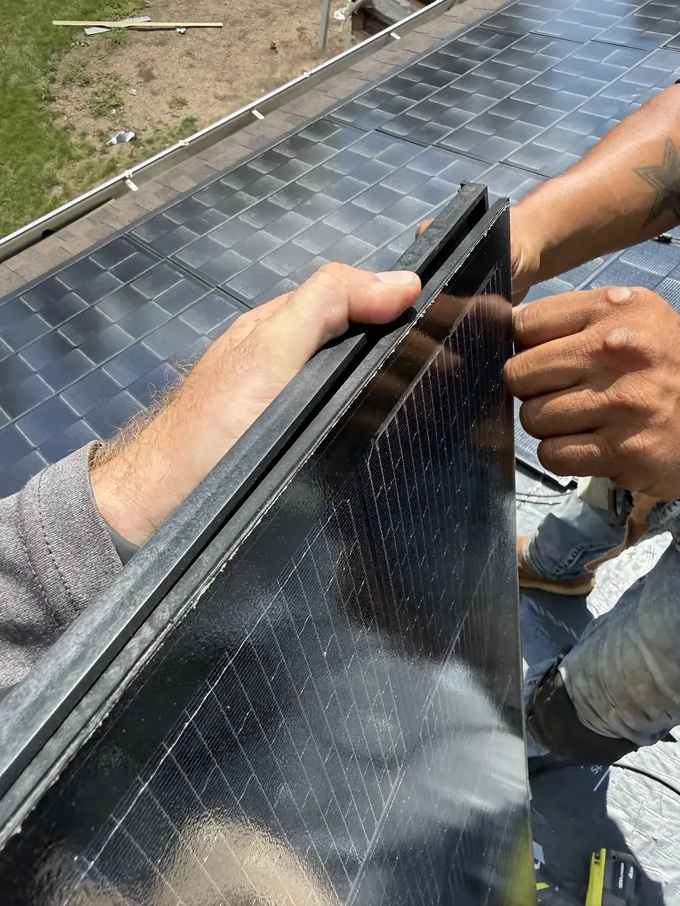 Two roofers holding a CertainTeed Solstice solar shingle showing its glass face and dark resin frame